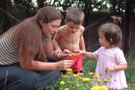 mom and kids looking at flower